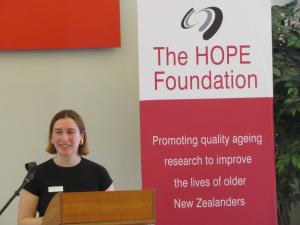 HOPE Scholar, Rosa speaking near the HOPE Foundation banner
