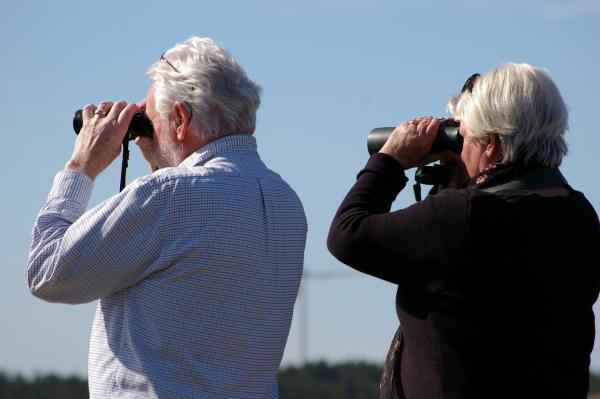 Two older people looking through binoculars